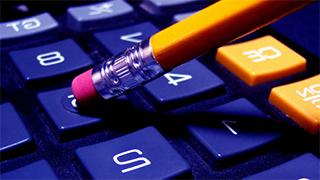 Close up image of the number keys on a calculator and the eraser end of a pencil being used to input numbers.